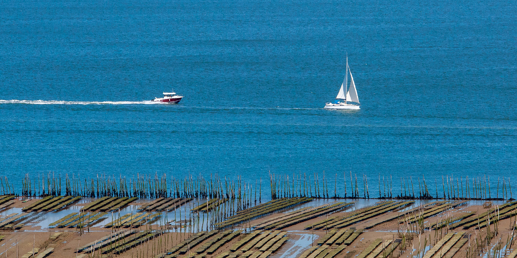 Bateau à moteur et voilier sur le bassin d'Arcachon