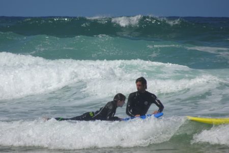 Moniteur de surf poussant une élève dans les vagues au Cap Ferret